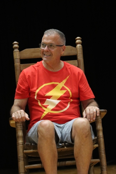 staff member sits in rocking chair on stage